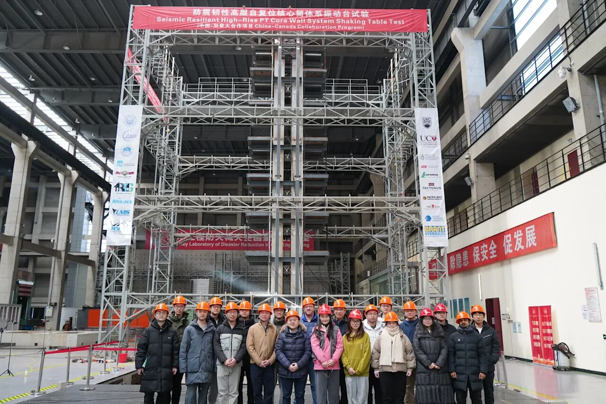 A team of researchers, including UBC structural engineering professor Tony Yang, stands in front of their high-rise model at a testing facility in Shanghai, where they conducted large-scale earthquake simulations. (UBC Smart Structures Lab - image credit)
